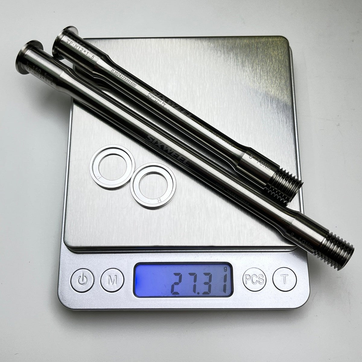 Sixweel titanium thru-axle pair weighing 27.3g on a scale